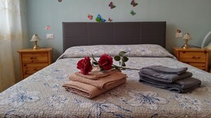 A neatly made bed with floral bedding, two nightstands with lamps, and decorative butterflies on the wall. - "Like at home" near Venice. (Venezia)