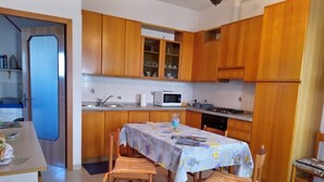 A kitchen with wooden cabinets, a dining table with chairs, a microwave, and a sink. - "Like at home" near Venice. (Venezia)