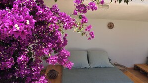 Een slaapkamer met een houten bed, een grijze sprei en een klein nachtkastje van hout.