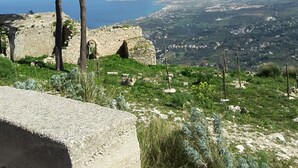 Un paisaje costero con vista despejada al mar, una montaña destacada y una construcción de piedra.