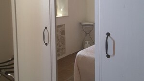 Un dormitorio con cama, una mesita y un espejo en la pared.