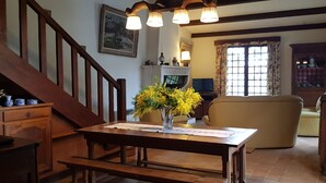 A wooden staircase, a dining table with a vase of yellow flowers, a sofa, and a television in a cozy living room. - House / Villa - RIVEDOUX  PLAGE (Rivedoux-Plage)