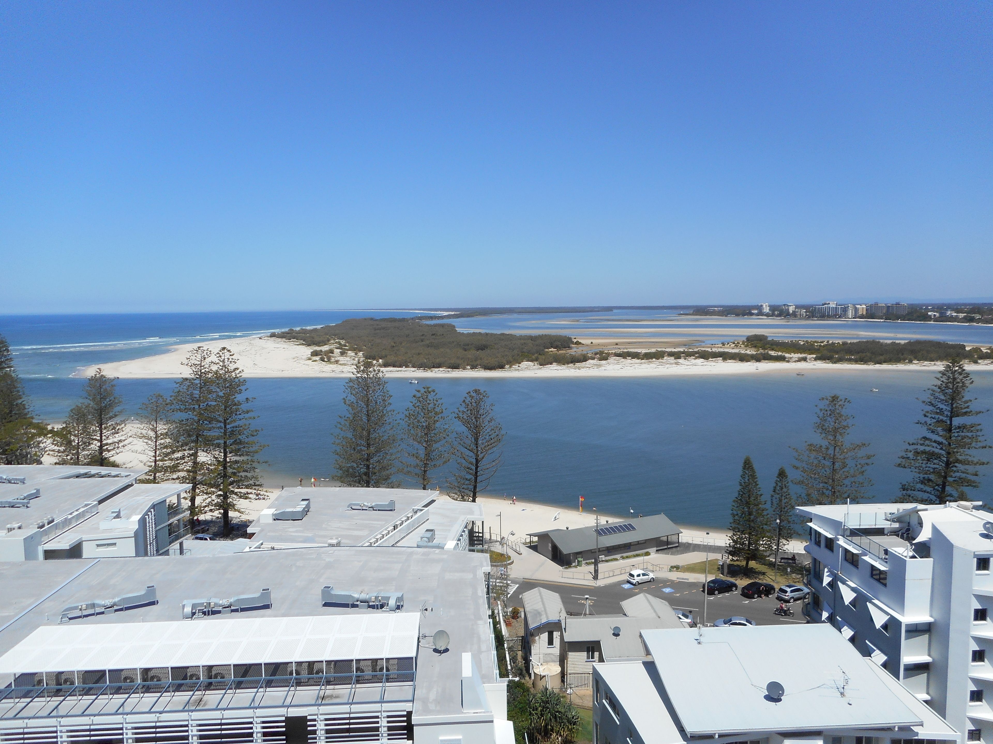 A coastal view with buildings, a beach, and clear skies.