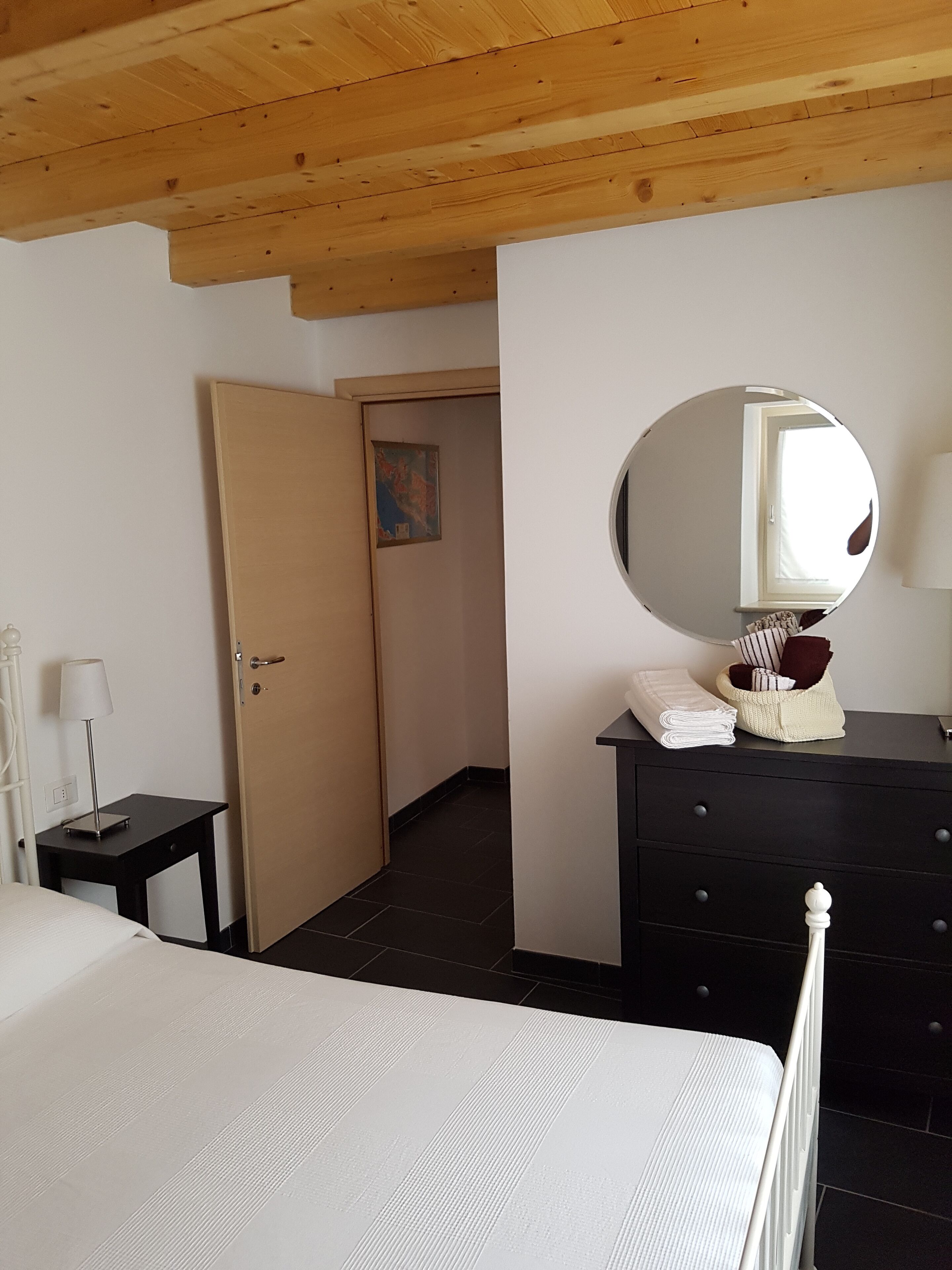A room with a bed, a dresser, a mirror, and a door leading to another room.