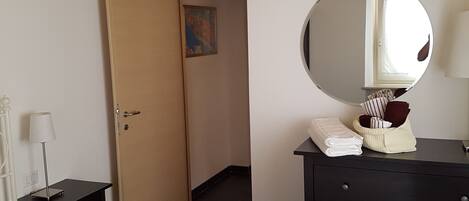 A room with a bed, a dresser, a mirror, and a door leading to another room.
