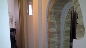 A hallway with a stone archway, a door, and a tiled floor. - Great Price... Romantic Apartment Near Beaches and Nightlife (Malcesine)
