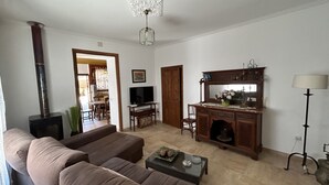A living room with a sofa, a television, a fireplace, a dining area, and a cabinet with a mirror. - Maria Ca Sa Padrina (Maria de la Salut)