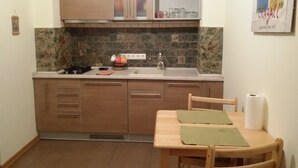 Une petite cuisine avec des meubles en bois, un évier et une table à manger avec des chaises.