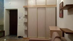 Une pièce dotée d’un placard avec porte coulissante, d’une petite table, d’un canapé et d’une étagère fixée au mur.