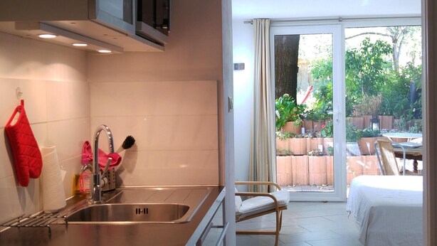 A modern kitchen with a stainless steel sink and a dining area with a table and chairs. - Garden in town (Lyon)