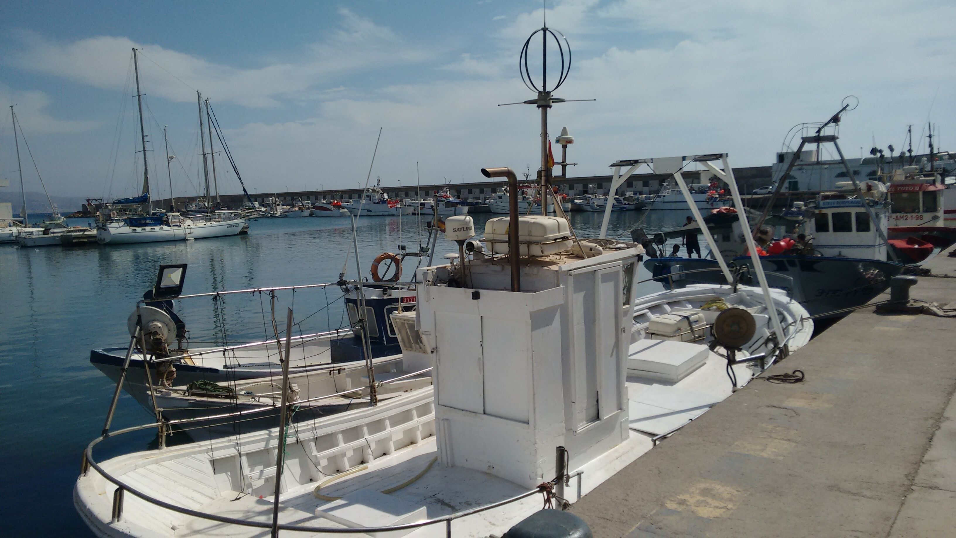 A marina with various boats docked, a lifebuoy, and a satellite dish on a boat.
