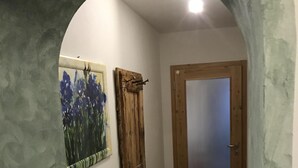 En gang med en trædør, en radiator og et blomsterbillede.