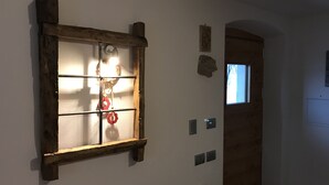 Et værelse med et vindue med træramme, en dør og en lampe monteret på væggen.
