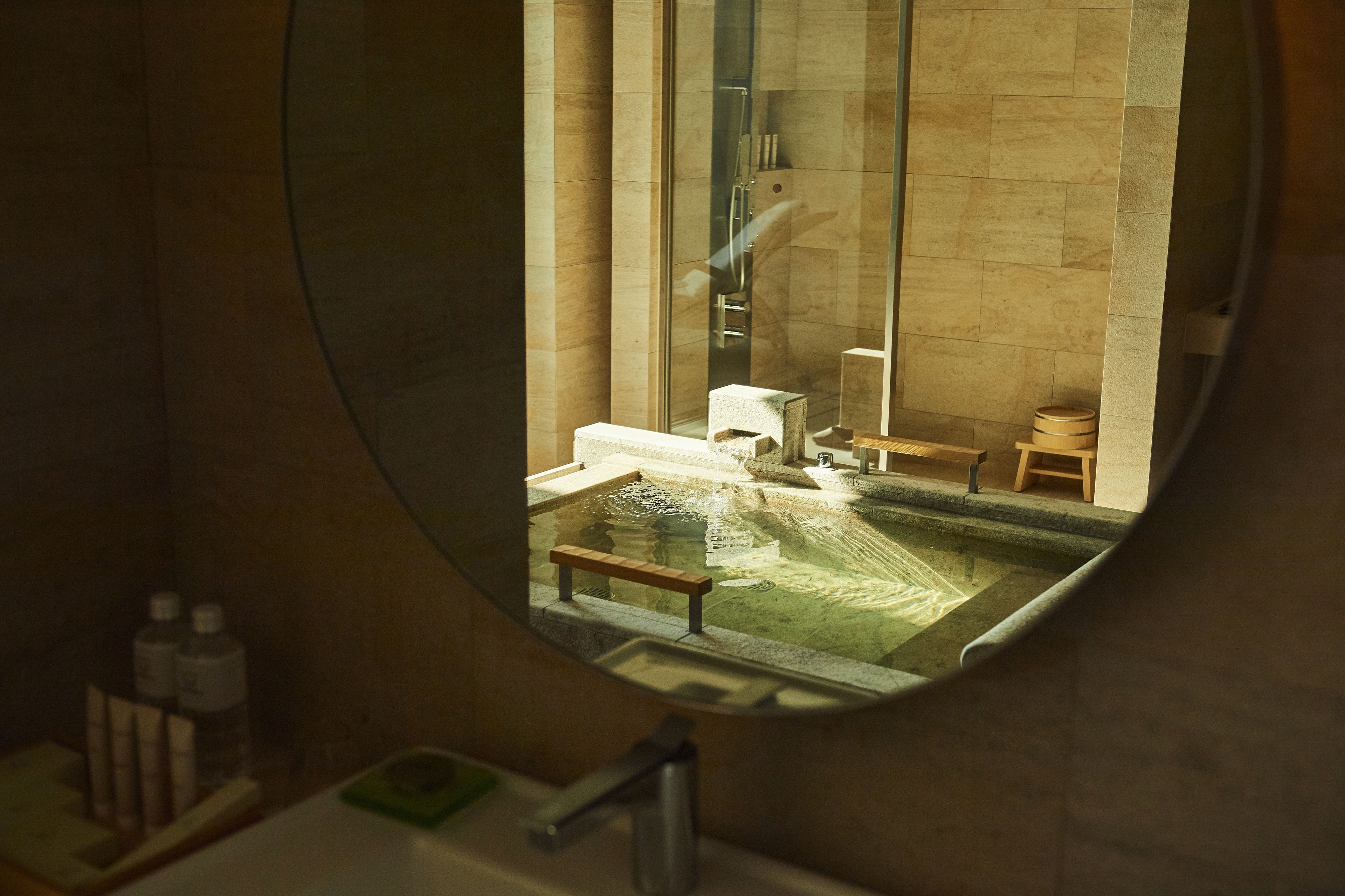 A bathroom with a round mirror, a sink, a bathtub, and a shower area.