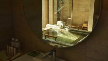 A bathroom with a round mirror, a sink, a bathtub, and a shower area.