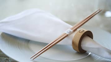 A white table setting with chopsticks and a wooden napkin holder.