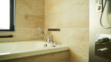 A bathroom with a bathtub, a faucet, and a towel dispenser.