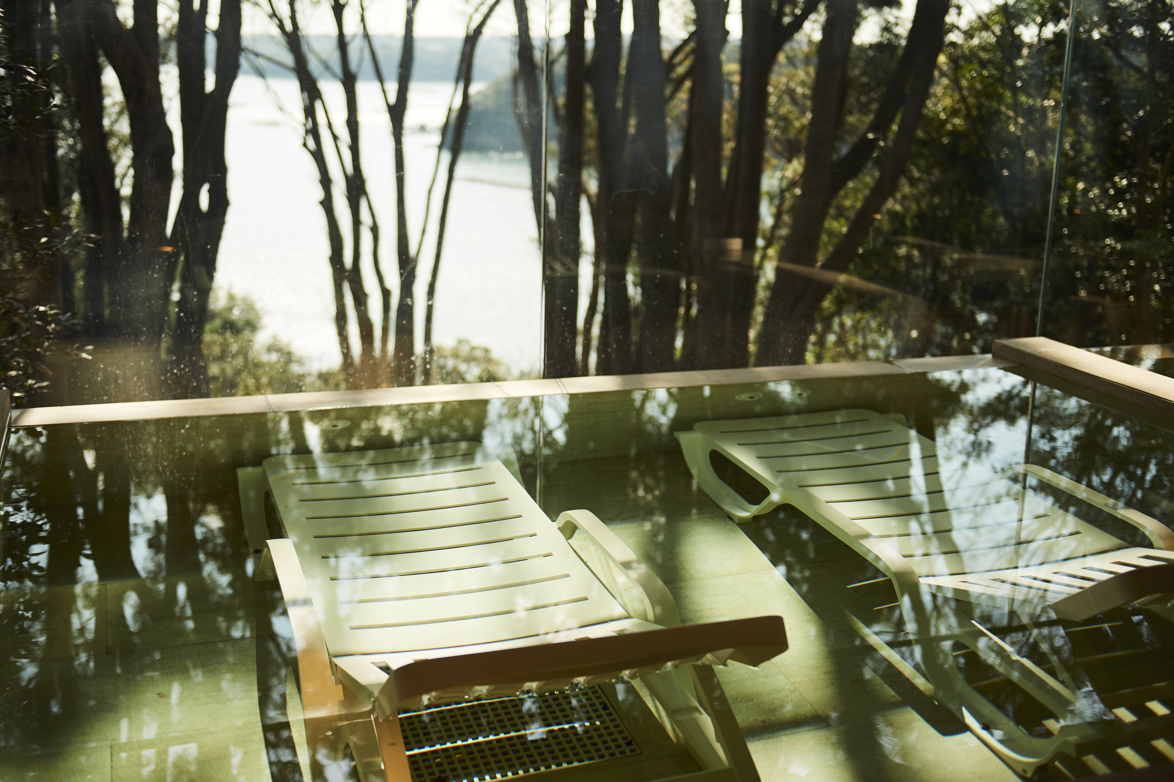 A glass-bottomed pool with lounge chairs.