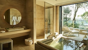 A modern bathroom with a large mirror, a sink, and a glass-enclosed shower. There is a small seating area with a bench and a chair outside the bathroom. - The Hiramatsu Hotels & Resorts Kashikojima (Shima)