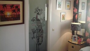 Un dormitorio con cama, una mesita de noche con lámpara y una pared decorada con cuadros.