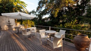 Eine Holzterrasse mit Sitzgelegenheiten im Freien, darunter Tische und Stühle, sowie ein großer Pflanzkasten.