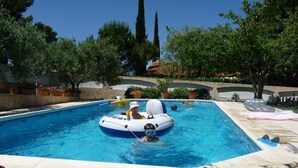 Une piscine avec une personne à bord d’un radeau gonflable bleu.
