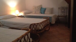 Ein Schlafzimmer mit zwei Einzelbetten, einem Nachttisch mit Lampe, einem Sessel und einer Treppe.