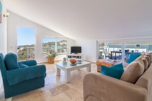 A spacious living room with a large window, a flat-screen TV, and a balcony with outdoor furniture. - Beautiful 2 Levels Romantic Luxury Stunning Views, Private Roof  Pool, Spacious  (Kalkan)