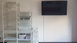 Una habitación con una estantería blanca, un televisor de pantalla plana montado en la pared y un suelo de baldosas.