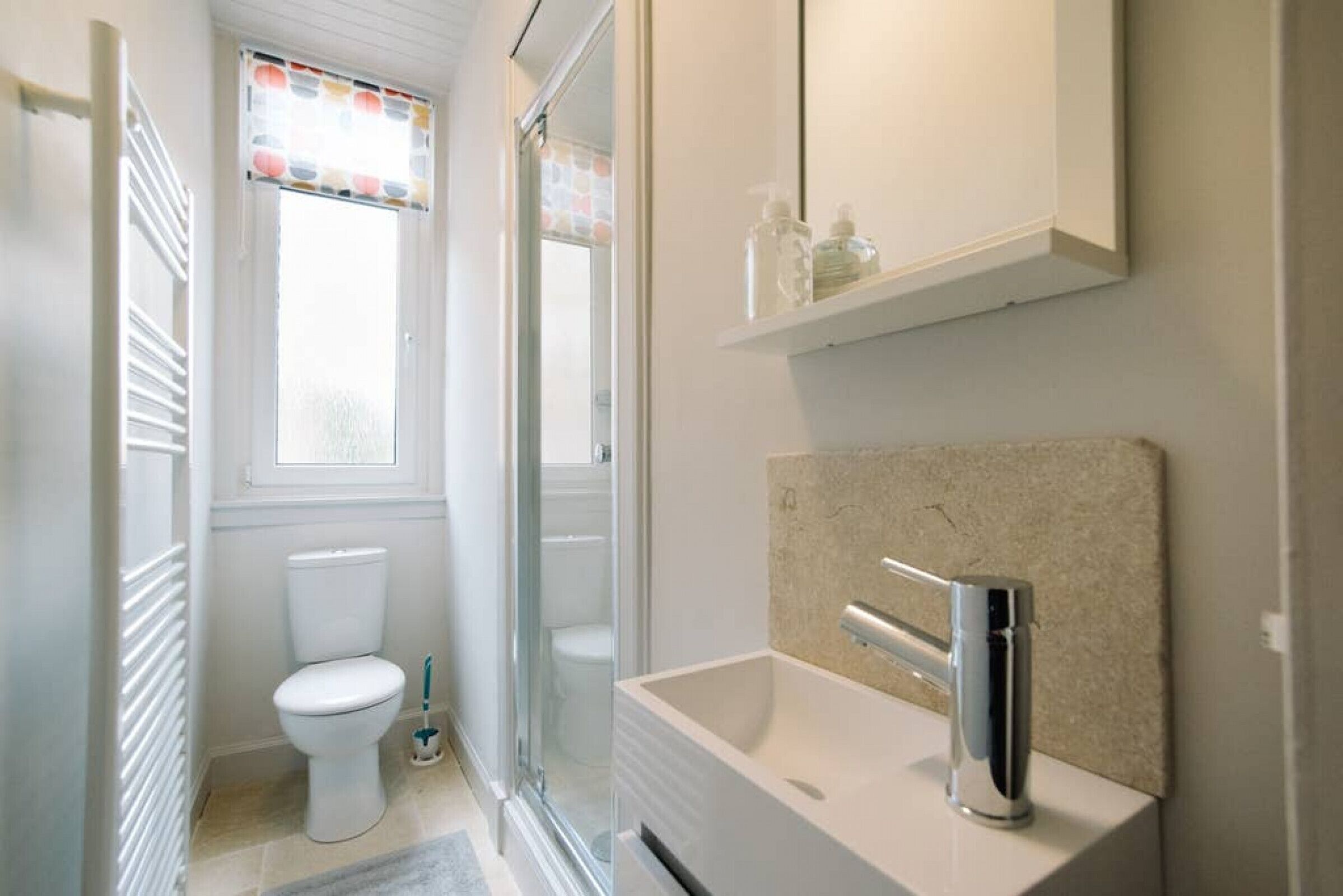 Un bagno moderno con il water bianco, una doccia e un lavandino con uno specchio sopra.