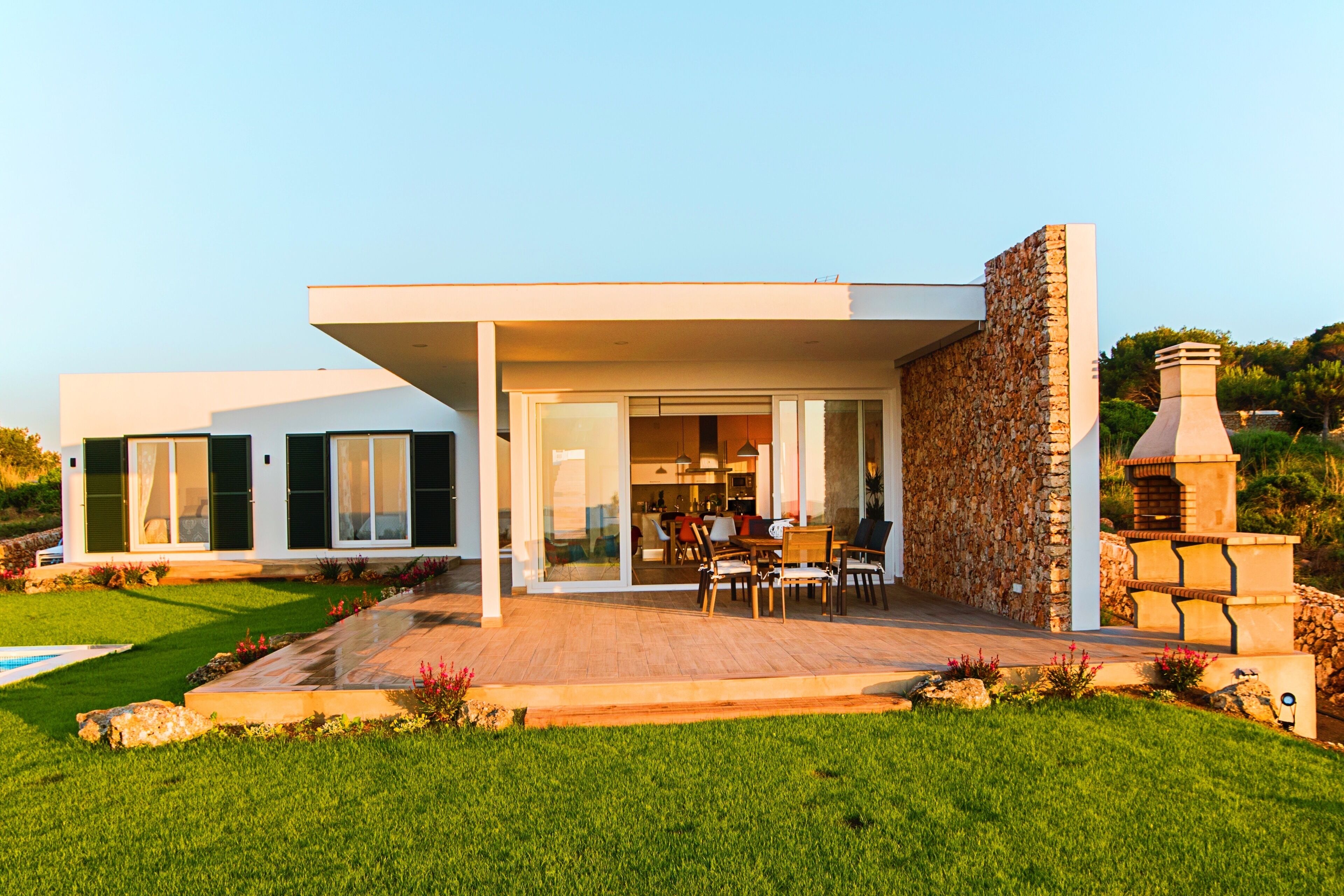 Une maison moderne dotée d’un patio, d’une piscine et d’un mur en pierre.