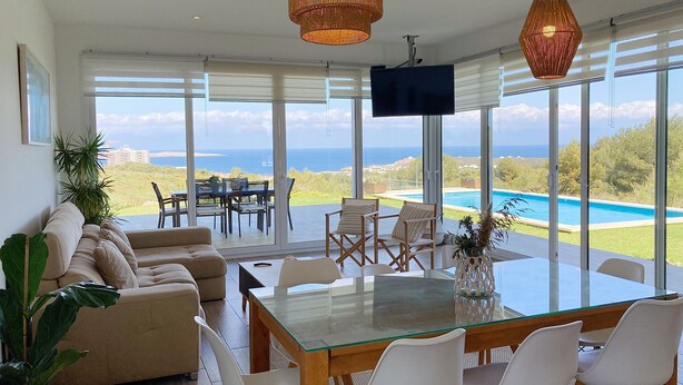A spacious living area with a glass dining table, comfortable seating, and a large TV screen.