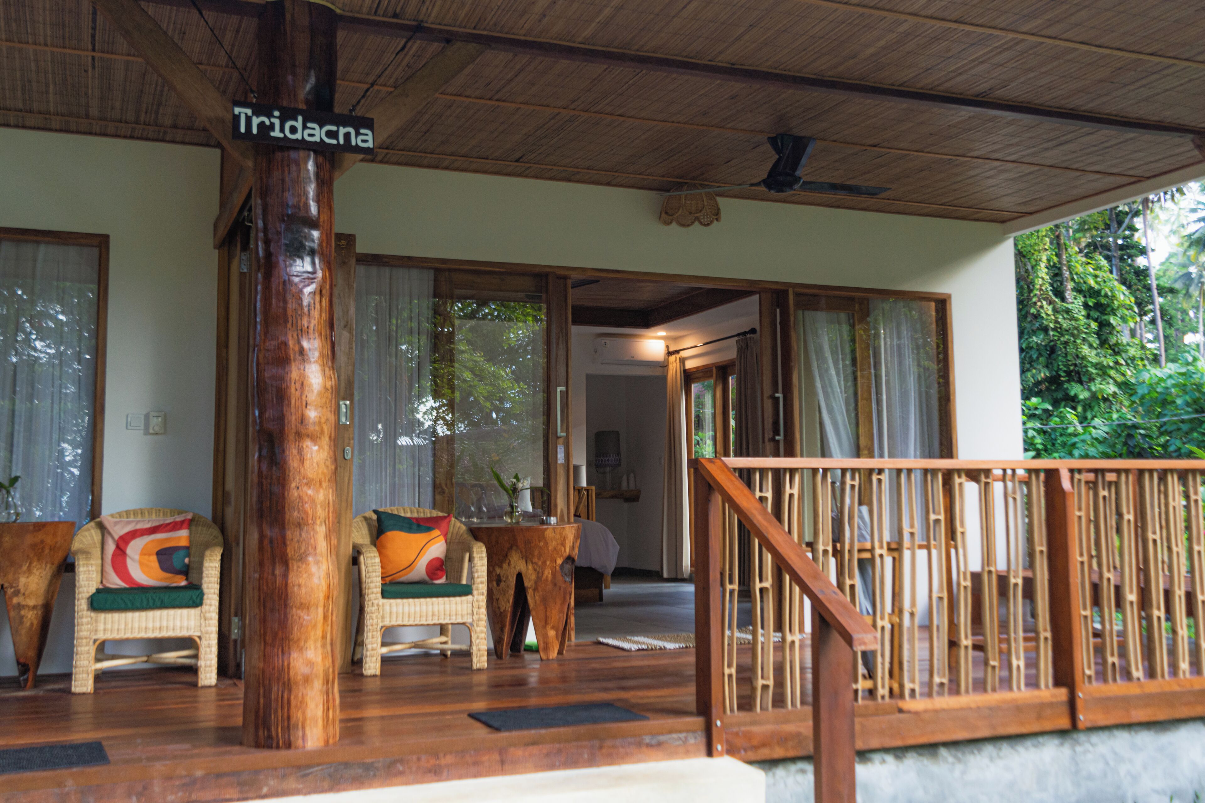 A wooden deck with wicker chairs and a sign reading "Tridacna."