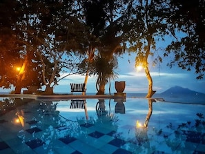An infinity pool with a checkered pattern, surrounded by trees and a bench. - Murex Manado Dive Resort (Pineleng)
