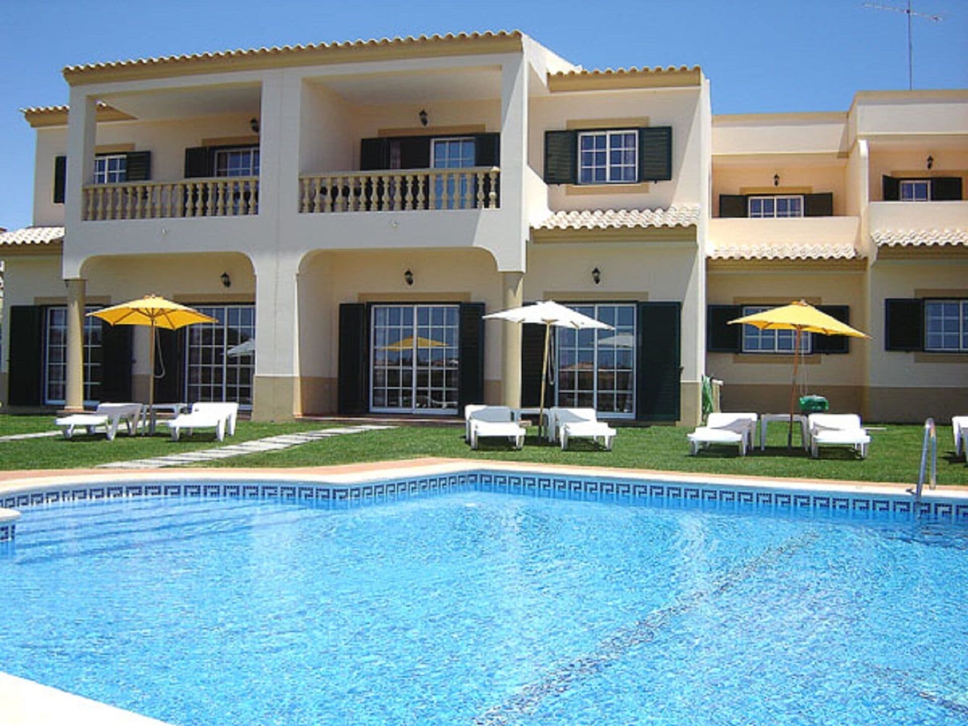 Un hôtel doté d’une piscine, de nombreux balcons et d’espaces extérieurs aménagés avec des parasols.