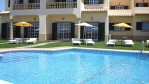 Un hotel con piscina, varios balcones y zonas de estar al aire libre con sombrillas.