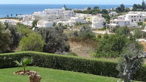 Una zona residencial costera con edificios blancos, césped verde y vista despejada al mar.
