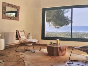 Relax in a serene space with a panoramic view of lush landscapes and distant mountains.