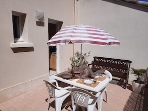 A patio with a table and chairs, an umbrella, and a potted plant. - Room with a terrace overlooking the ocean. A comfortable home just 40 m from the beach, (Saint-Michel-Chef-Chef)