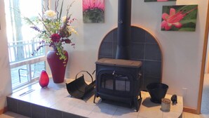 A room with a fireplace, a large vase with flowers, and wall art. - Neil Bay Waterfront Family And Pet Friendly Property!<br>PCUP00-13-0010  (Roche Harbor)
