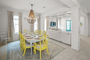 A dining area with a white table, yellow chairs, and a chandelier. - Magazine Gorgeous Orange Beach Oasis - 5 BR, Family, Bikes, Beach, Relax (Orange Beach)