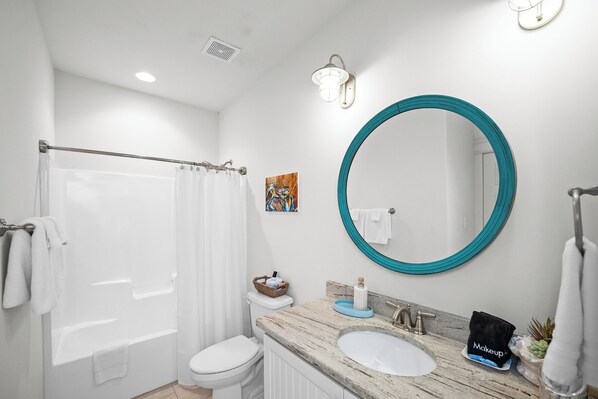 A bathroom with a bathtub, toilet, sink, and a large mirror.