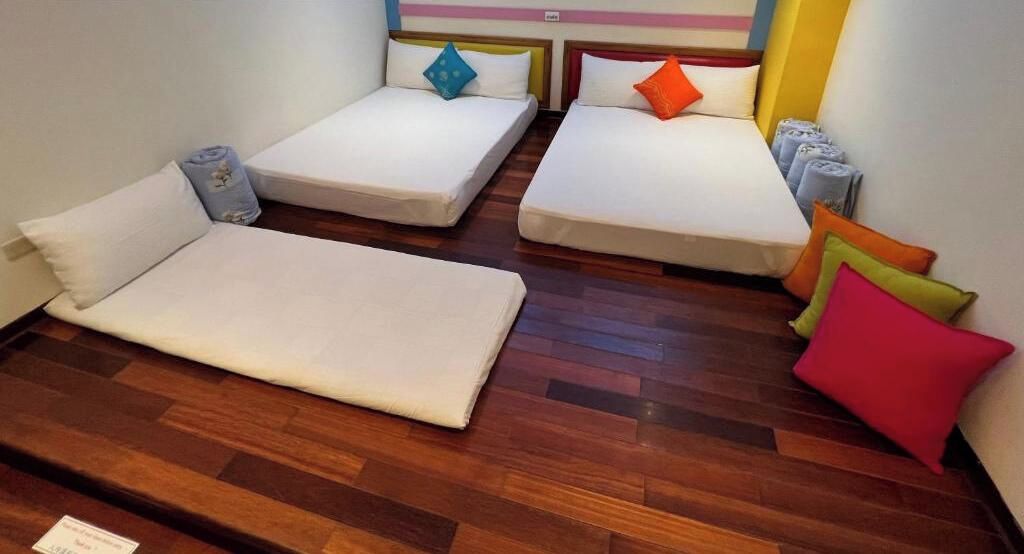 Une chambre avec quatre lits disposés en carré, chacun étant muni d’un oreiller et d’une serviette roulée.