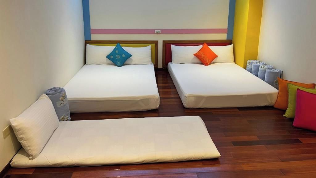 A hotel room with two single beds, a sofa bed, and a small table.