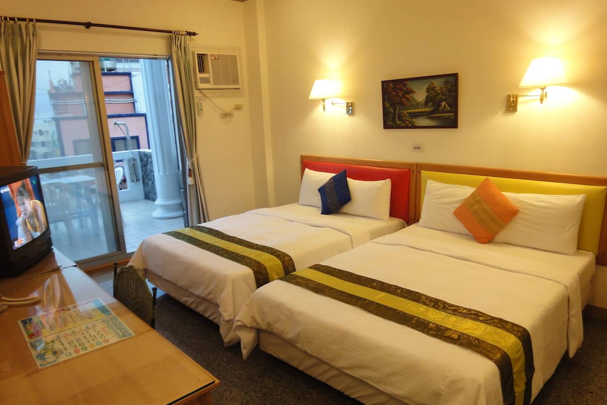 A hotel room with two beds, a TV, and a table with a menu.