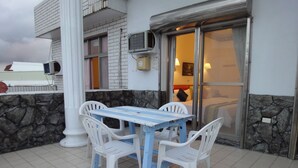 A patio with a table and four chairs, a stone wall, and a glass door leading to a room. - Formost Hotel (Hengchun)