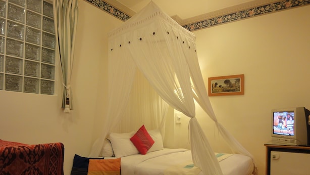 A bedroom with a bed, a television, a window with curtains, and a patterned sofa. - Formost Hotel (Hengchun)