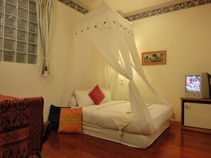 A bedroom with a bed, a television, a window with curtains, and a patterned sofa. - Formost Hotel (Hengchun)