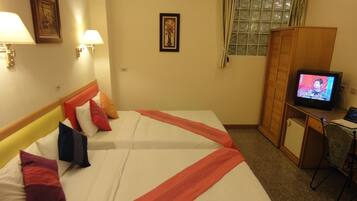 A hotel room with two beds, a television, a desk, and a wardrobe.