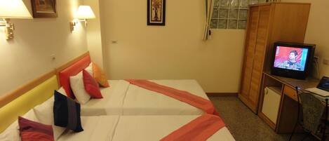 A hotel room with two beds, a television, a desk, and a wardrobe.